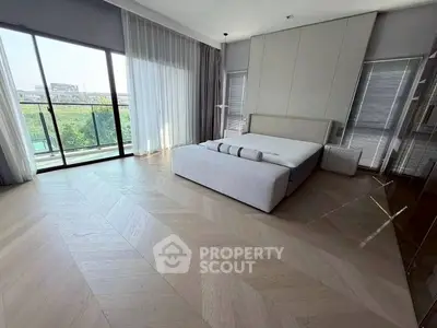 Spacious modern bedroom with large windows and balcony access, featuring sleek design and natural light.