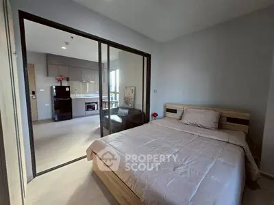 Modern bedroom with sliding glass doors leading to a cozy living area and kitchen.