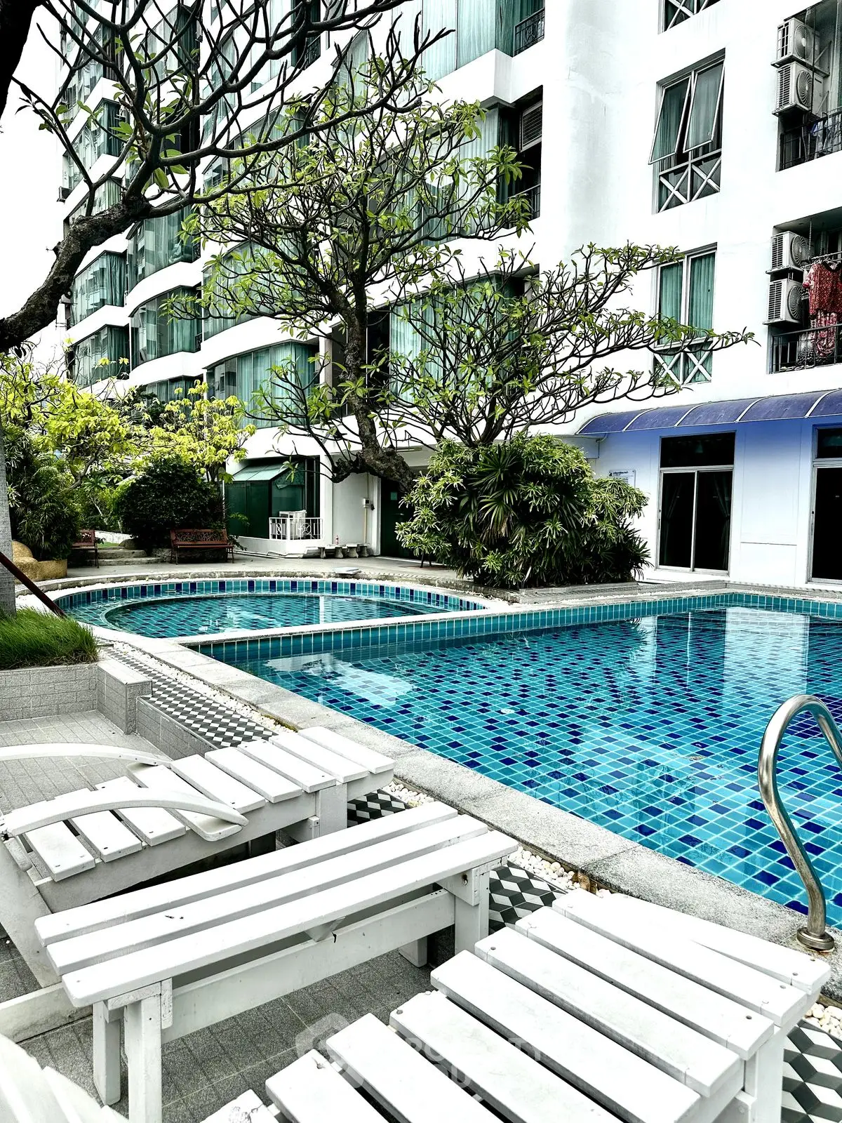 Luxurious apartment complex with stunning pool and lush greenery, perfect for relaxation and leisure.