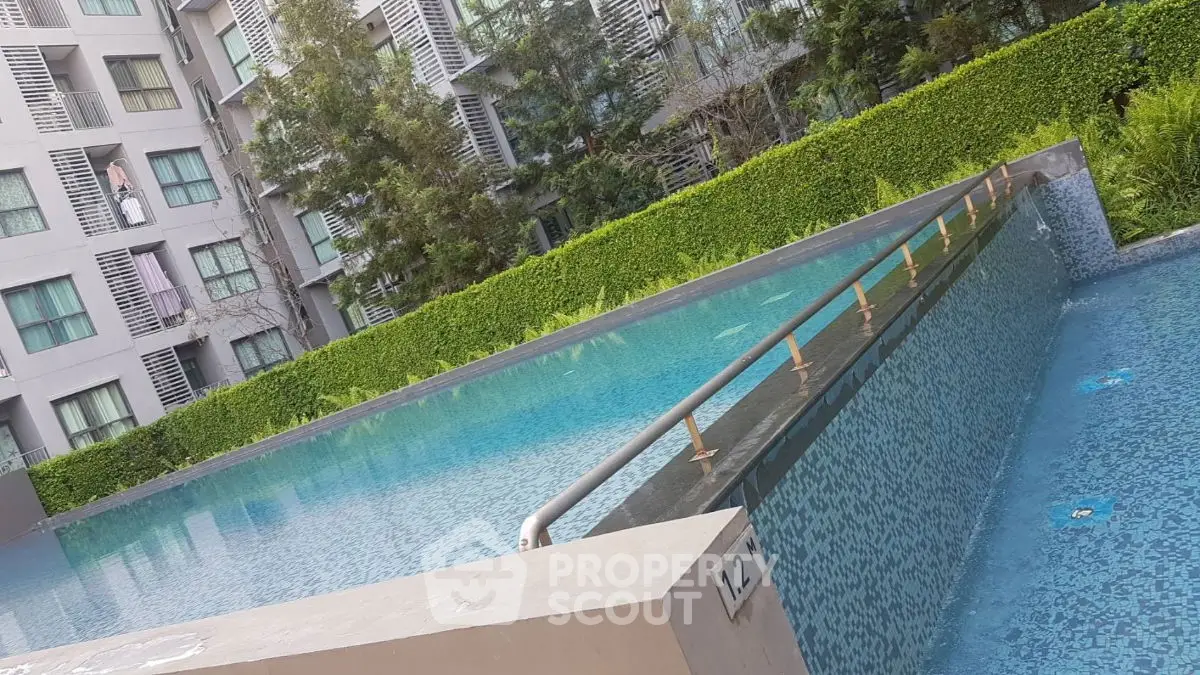 Luxurious modern apartment complex with stunning infinity pool and lush greenery.