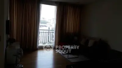 Cozy living room with large window and city view, featuring modern furniture and wooden flooring.