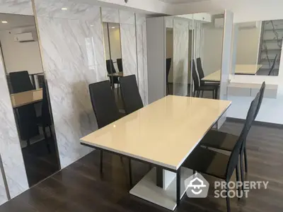 Modern dining area with sleek table and chairs, mirrored walls enhancing space and light.