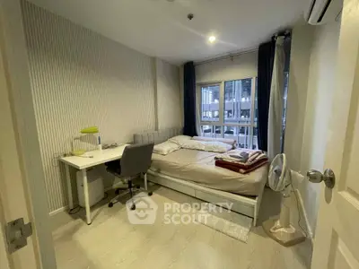 Modern bedroom with study desk and large window view in urban apartment.