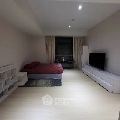 Spacious modern bedroom with sleek furniture and large window view.