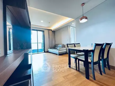Spacious modern living room with dining area and balcony access, featuring elegant wooden flooring and stylish furniture.