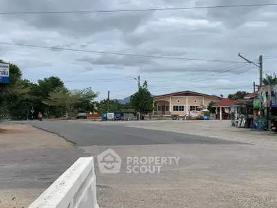 Charming suburban street view with commercial buildings and lush greenery.