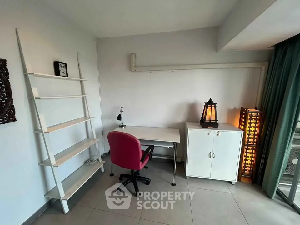 Modern study room with sleek desk, red chair, and stylish shelving in a bright apartment.