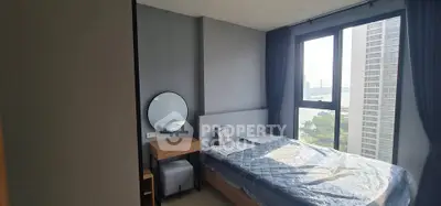 Modern bedroom with large window offering stunning city view, featuring stylish decor and cozy ambiance.