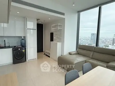 Modern living room with city view, featuring sleek furniture and integrated kitchen appliances.