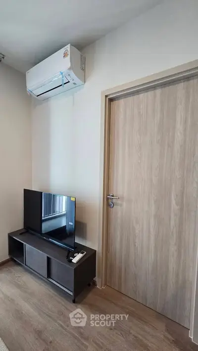 Modern living room with sleek TV setup and air conditioning unit, perfect for cozy entertainment.