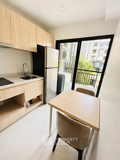 Modern kitchen with wooden cabinets, dining table, and balcony view in a stylish apartment.