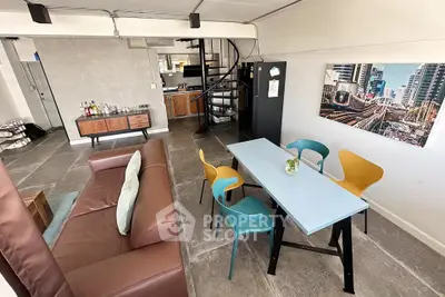 Stylish open-plan living room with modern furniture and spiral staircase in urban apartment.