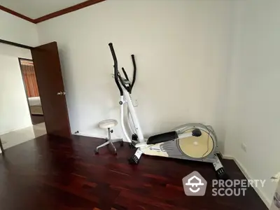 Spacious room with exercise equipment and wooden flooring in modern home.