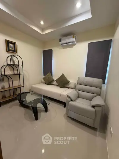 Cozy living room with modern furniture and air conditioning, perfect for relaxation.