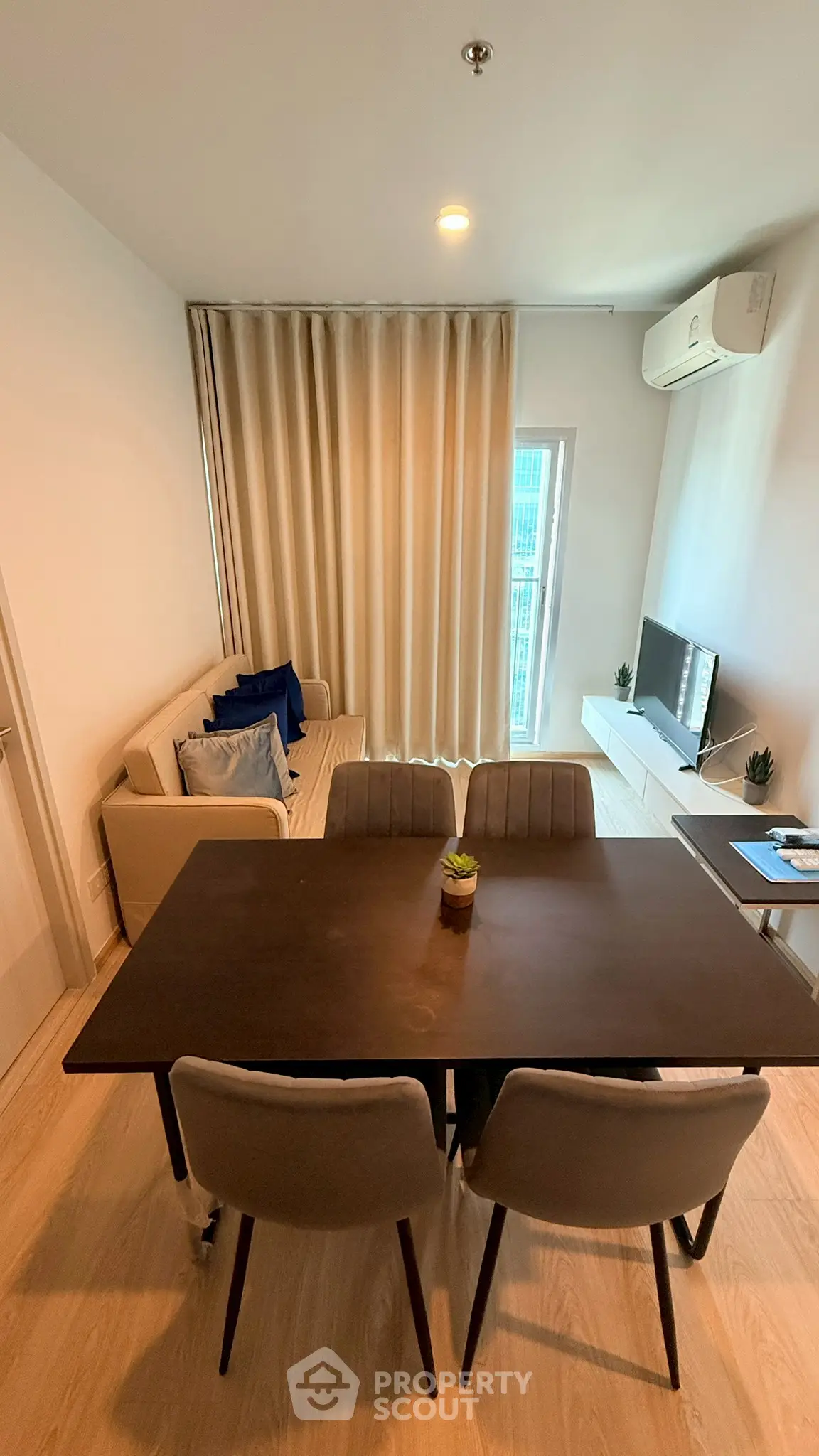 Modern living room with dining area, cozy sofa, and flat-screen TV, perfect for urban living.