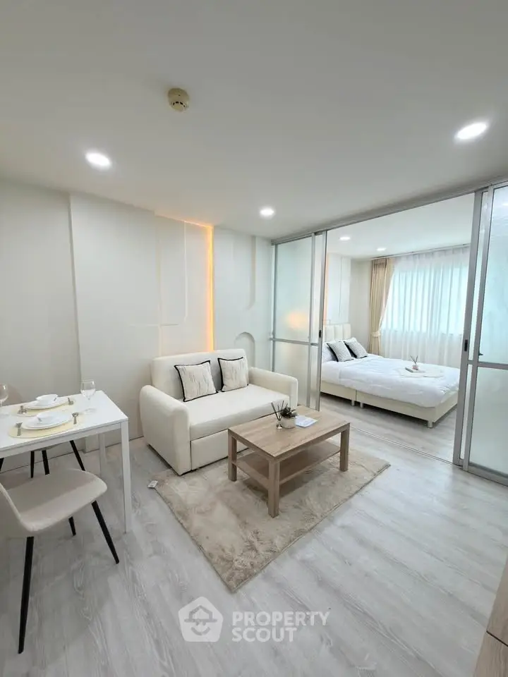 Modern open-plan living room with cozy bedroom, elegant decor, and natural light in a stylish apartment.