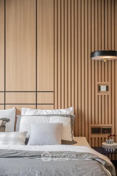 Modern bedroom with stylish wood paneling and elegant lighting fixture.
