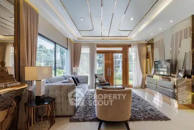 Luxurious living room with elegant decor and large windows offering garden views.