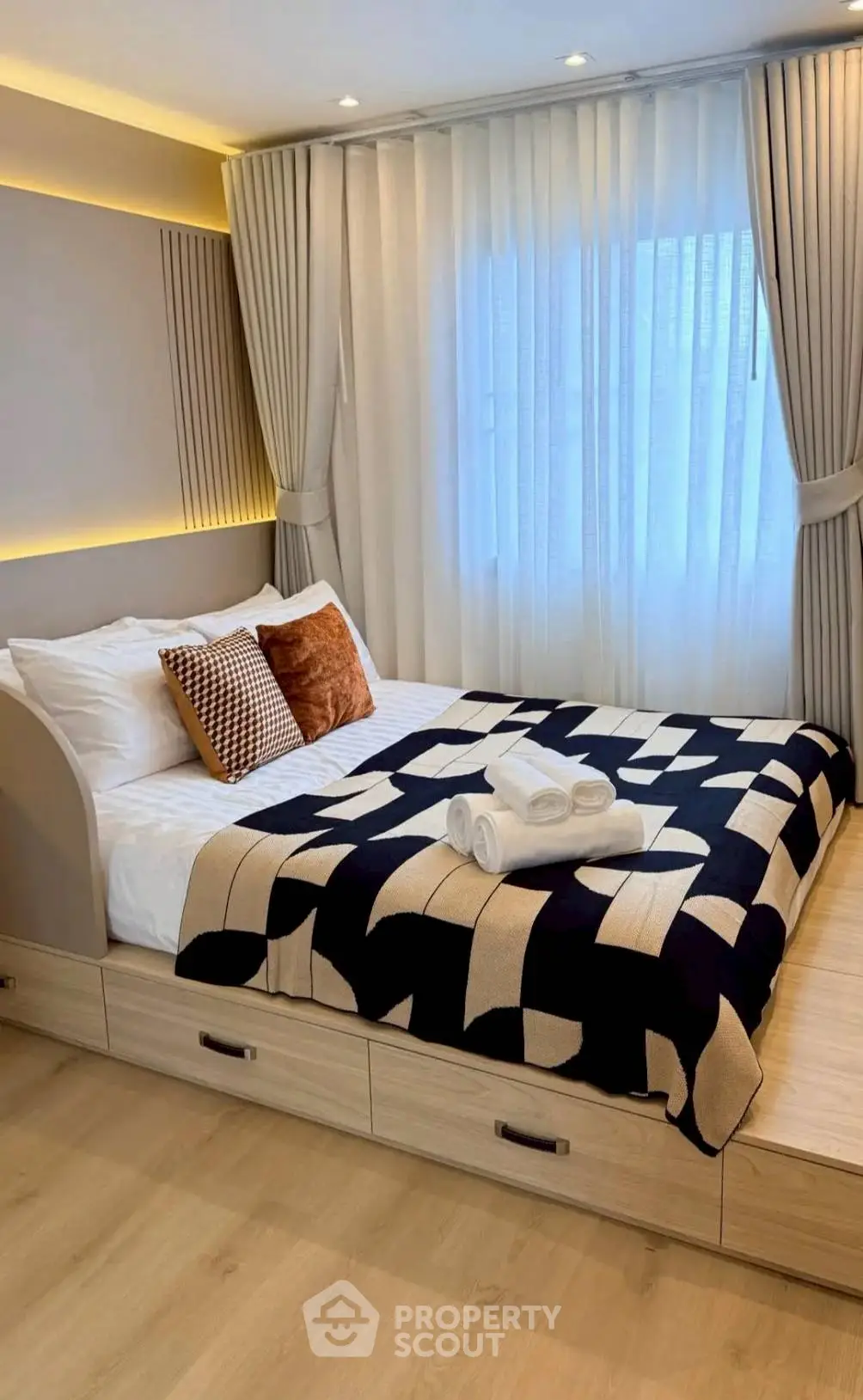 Modern bedroom with stylish decor and natural light, featuring a cozy bed and elegant curtains.