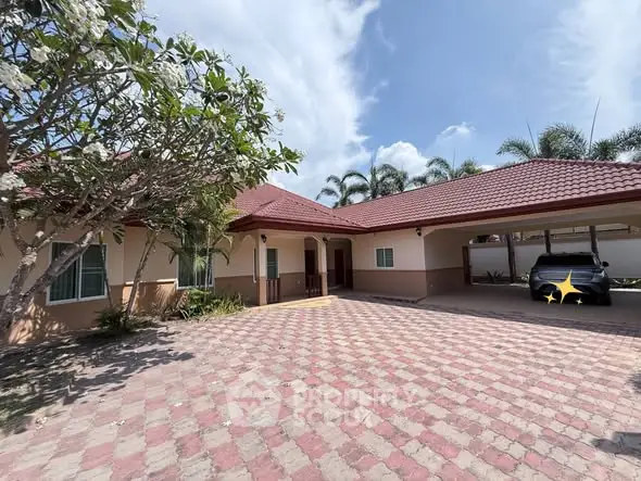 Charming single-story home with spacious driveway and carport, surrounded by lush greenery and palm trees.