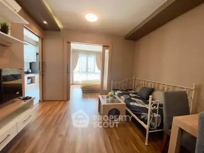 Charming living room with cozy decor and natural light, featuring a stylish daybed and modern entertainment setup.