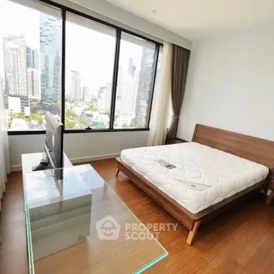 Spacious bedroom with city view and modern furnishings in high-rise apartment.