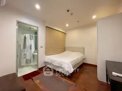 Cozy bedroom with ensuite bathroom and wooden flooring in modern apartment