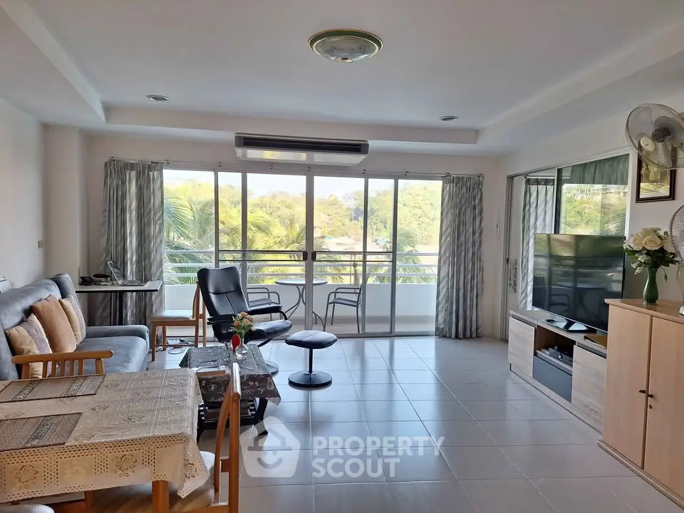 Spacious living room with large windows and balcony offering scenic views, perfect for relaxation and entertainment.