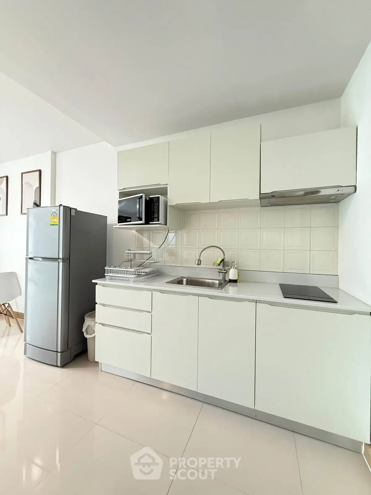 Modern kitchen with sleek white cabinets and stainless steel appliances in a bright apartment.