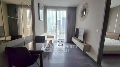 Modern living room with sleek furniture and city view, adjacent to a cozy bedroom.