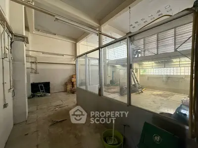 Spacious industrial-style interior with high ceilings and large windows, ideal for creative workspace or studio.
