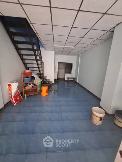 Spacious interior with blue tiled floor and staircase, ideal for creative renovation.