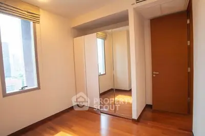 Bright bedroom with wooden flooring and mirrored wardrobe