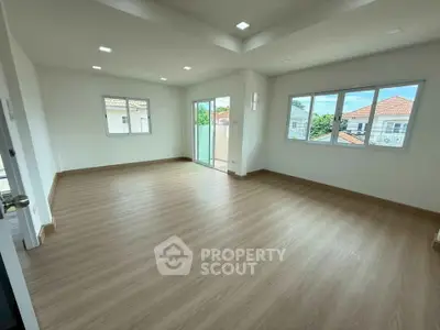 Spacious empty room with large windows and wooden flooring, perfect for customization.