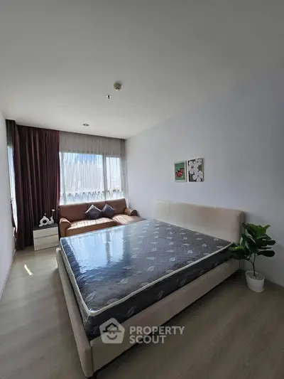Spacious bedroom with large window and cozy seating area, perfect for relaxation.
