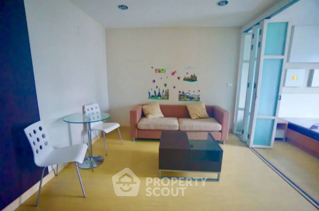 Cozy living room with modern furniture and glass table, perfect for relaxation.