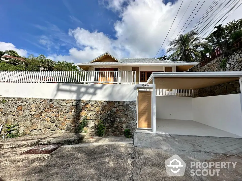 Charming hillside home with spacious driveway and modern design in tropical setting.