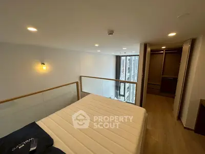 Modern loft bedroom with large window and wooden flooring, featuring a walk-in closet.