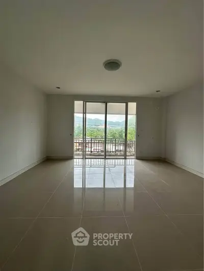 Spacious empty living room with large windows offering scenic views and ample natural light.