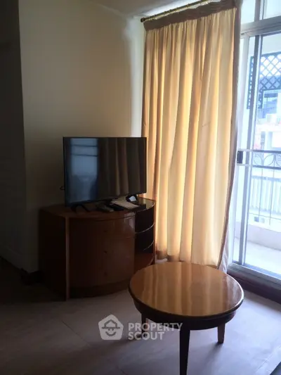 Cozy living room with TV and balcony access, perfect for relaxation.