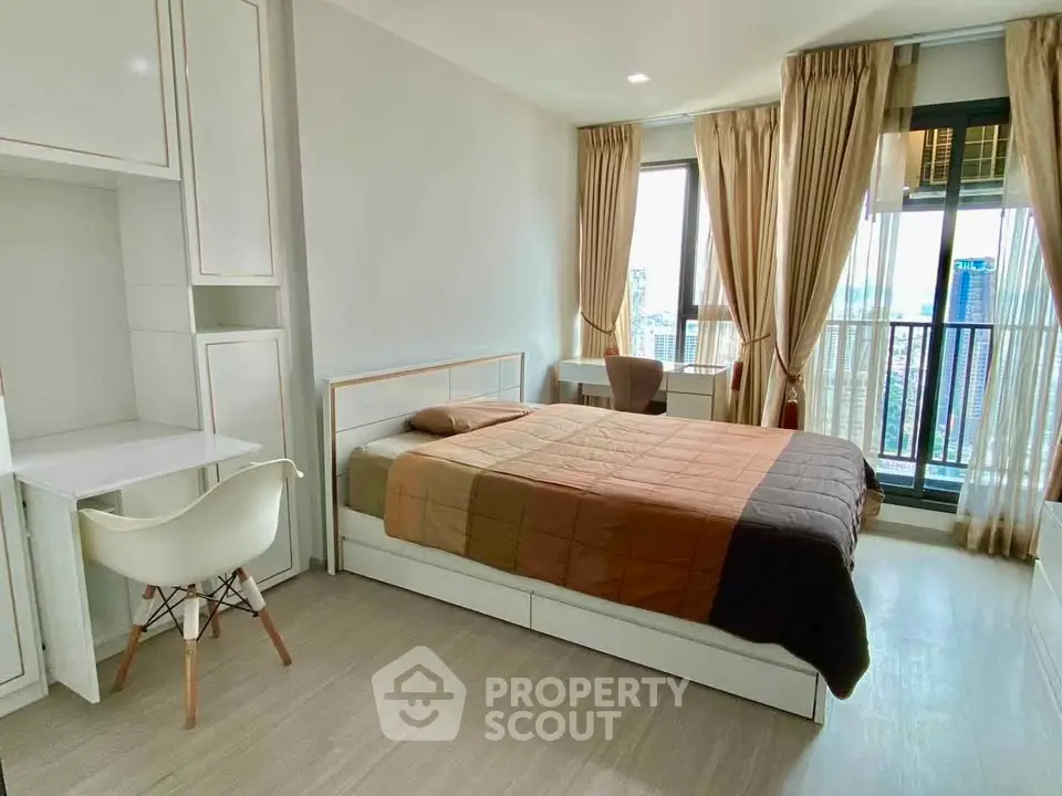 Modern bedroom with city view, featuring a cozy bed, study desk, and large windows for natural light.