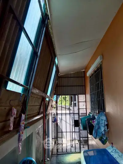 Narrow balcony with metal bars and slanted windows, ideal for storage or utility use.