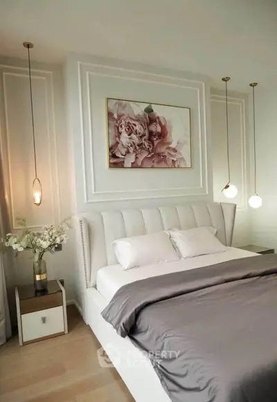 Luxurious bedroom with elegant decor and plush bedding, featuring modern pendant lights and floral artwork.