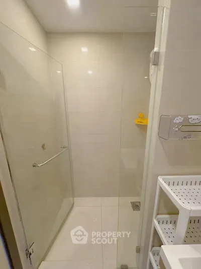 Modern bathroom with glass shower enclosure and sleek white shelving.