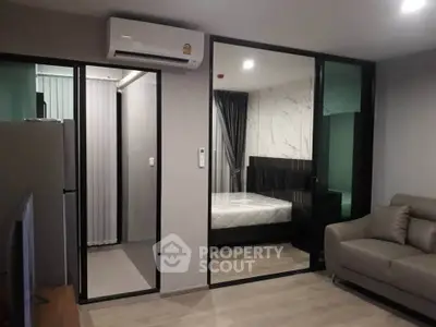 Modern studio apartment with glass partition, featuring a cozy living area and bedroom.