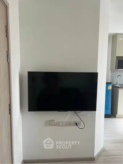 Modern apartment interior with wall-mounted TV and sleek kitchen design.