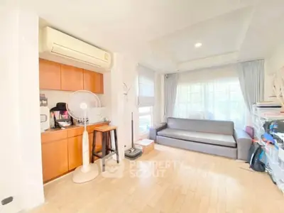Bright living room with wooden flooring and cozy sofa, featuring air conditioning and natural light.
