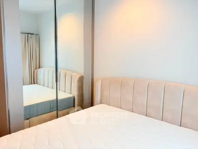 Modern bedroom with mirrored wardrobe and stylish upholstered bed.