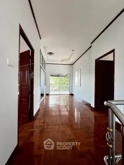 Spacious hallway with polished wooden floors and natural light, ideal for elegant living.