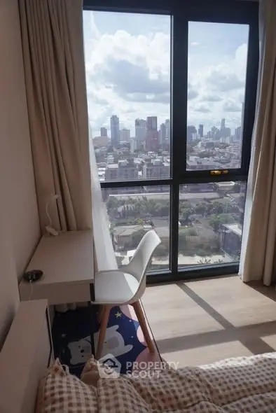 Cozy bedroom with city view, featuring a desk and chair by the window.